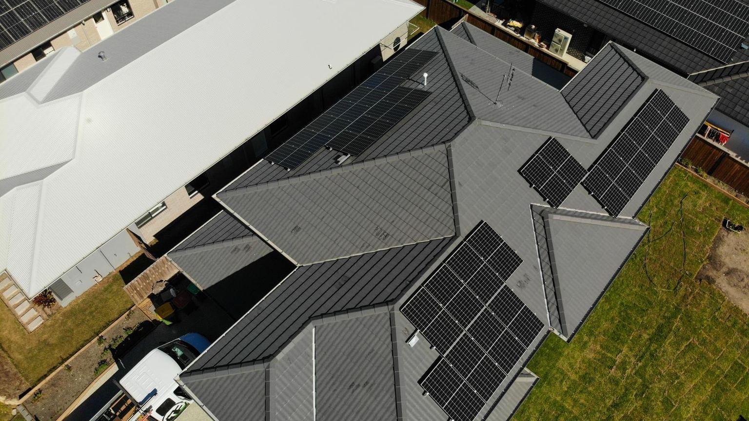 Aerial view of a family home in a new estate with solar panels across its grey tiled roof