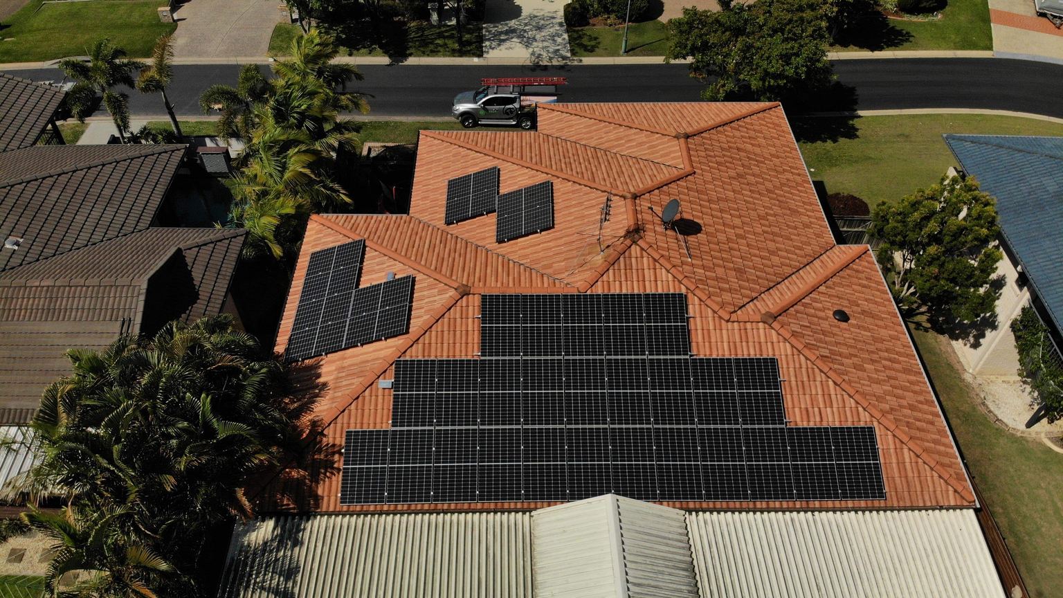 Aerial view of a suburban home with solar panels laid out across its terracotta tiled roof