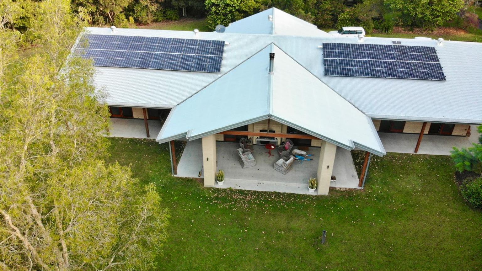 Aerial view of a single-storey home with a verandah and two solar arrays on its metal roof