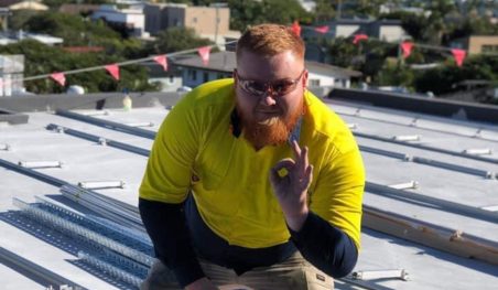 A Thomas installer in hi-vis on a roof beside a solar array